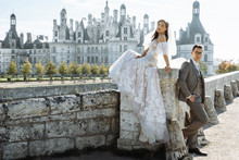 Old Castle. Beautiful And Stylish Bride And Groom Posing Against The Backdrop Of The Castle In France On Their Wedding Day