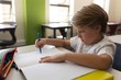 © WavebreakMediaMicro - Schoolboy studying in classroom sitting at desks in school