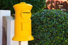 Yellow Post Box In Green Garden. Decorative Postbox Closeup Photo. Vintage Mail Box And Green Hedge.