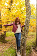 © Esteban Martinena - A young girl with reddish hair balances on a fallen trunk on the ground in an autumnal forest