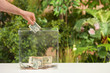 Man putting money into donation box on table against blurred background, closeup. Space for text