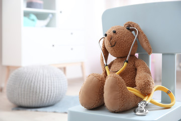 Wall Mural - Toy bunny with stethoscope on chair indoors, space for text. Children's doctor