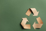 Fototapeta  - Recycling symbol cut out of kraft paper on green background, top view. Space for text