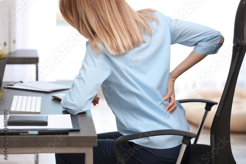 Fotomural Young woman suffering from back pain in office