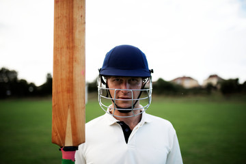 Wall Mural - Cricket player holding a bat on the field