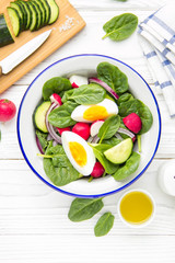 Canvas Print - Fresh spring salad with spinach, radish, cucumber and egg. Delicious lunch, healthy food, summer vegetables. In bowl on white background