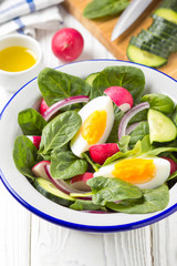 Canvas Print - Fresh spring salad with spinach, radish, cucumber and egg. Delicious lunch, healthy food, summer vegetables. In bowl on white background