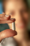 Fototapeta Lawenda - Girl observing a pill between two fingers