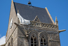 Historic Church Of Sainte Mere L'eglise, With A Paratrooper  Hanging On The Bell Tower In Normady, France.