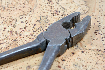 Old rusty pliers on cork background. Close up