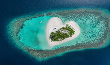 Drone Aerial View Of Beautiful Tropical Heart Shaped Island Among Blue Sea Water At Maldives Paradise With Boat On Background