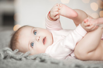 Wall Mural - Cute litttle baby at home in the bedroom. An infant indoors. 6th month child portrait. Adorable cute baby girl.