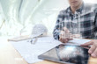 © ChayTee - Engineer or Architect looking and touching interface with building design reality virtual technology on computer tablet at modern office on site . Building automation digital wireless control concept
