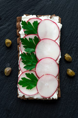 Sticker - Snack with ricotta and radish on a black background, top view