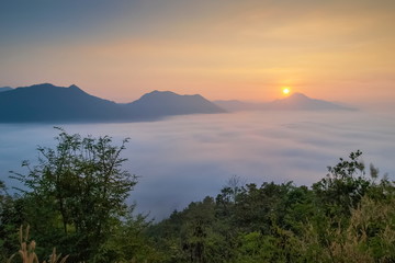 sunrise at Phu Thok, beautiful mountain view misty morning of top mountain around with sea of mist with colorful yellow sun light in the sky background, Chiang Khan District, Loei, Thailand.