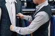 © DragonImages - Cropped image of tailor fitting bespoke suit to client in atelier
