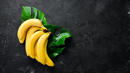 Wall Mural - Fresh yellow bananas on a black stone table. Top view. Free copy space.