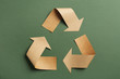 Recycling symbol cut out of kraft paper on green background, top view