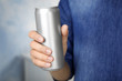 Woman holding aluminum can with beverage on blurred background, closeup. Space for design