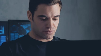 developer programmer working on computer in a data center filled with monitor screens. Steadicam shot