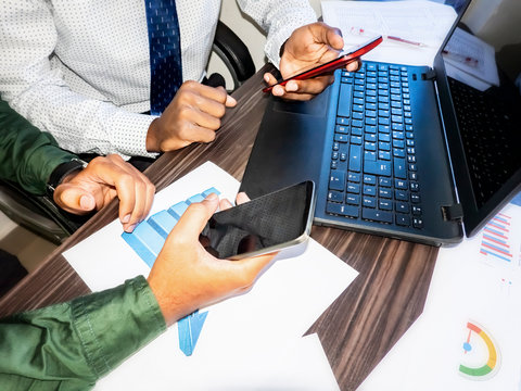 Close up business young adults men with smartphone laptop on desk with graphs