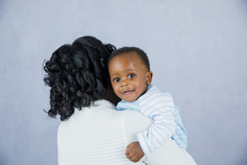 Wall Mural - Beautiful African Amercian Woman wHolding Her Baby boy on a Gray Background