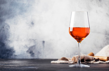 Trendy food and drink, orange wine in glass, gray table background, space for text, selective focus