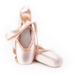 Pointe shoes ballet dance shoes with a bow of ribbons beautifully folded on a white background with a lot of light.