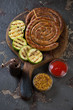 © Nickola_Che - Grilled rolled sausages with zucchini and dipping sauce on a rustic wooden serving board, studio shot