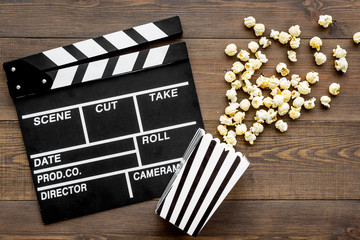 Film watching concept. Clapperboard and popcorn on dark wooden background top view