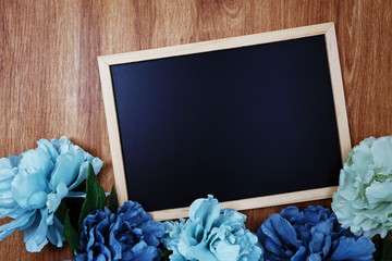 Wall Mural - space copy on blackboard with flower decoration top view on wooden background