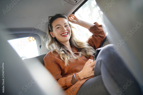 Fotomural Attractive young woman smiling at camera sitting in back of taxi
