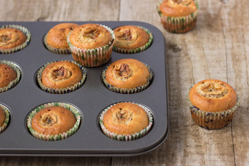 Homemade banana chocolate muffins in a baking form on a wooden background