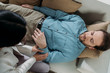 overhead view of hypnosis holding wrist of bearded man with closed eyes lying on couch