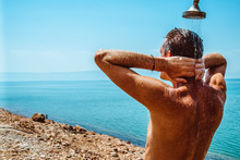 Men Is Having A Fresh Shower At The Beach. Dead Sea. Jordan