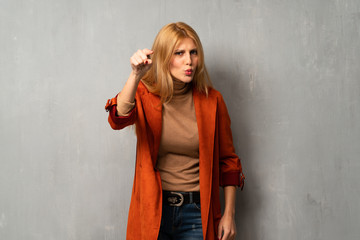 Woman over textured background frustrated by a bad situation and pointing to the front