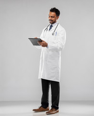 Wall Mural - medicine, technology and healthcare concept - smiling indian male doctor in white coat with tablet computer and stethoscope over grey background