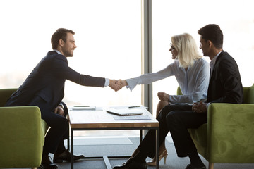 Wall Mural - Happy middle aged businesswoman handshaking smiling businessman welcoming new partner at meeting, friendly female and male business people shaking hands, respect introduction, gender equality concept