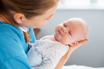 Wall Mural - cropped shot of young mother carrying adorable baby in hospital room