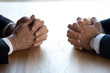 © fizkes - Clasped hands of two business men negotiators opponents opposite on table as politicians dialogue debate, applicant hr job interview, negotiating competitors, rivals confrontation challenge concept