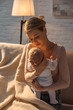 © LIGHTFIELD STUDIOS - young mother sitting on couch and holding baby during breastfeeding at night