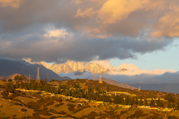 Wall Mural - Cloudy snow capped mountains behind urban hillside with homes and powerlines.