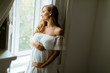 © BGStock72 - Young pregnant woman standing by the window