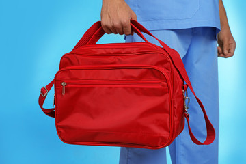 Wall Mural - Male doctor with first aid kit on color background, closeup. Medical object