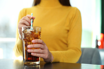 Wall Mural - Woman with glass of refreshing cola at table indoors, closeup. Space for text