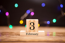 February 3rd. Day 3 Of February Month Set On Wooden Calendar At Center Of Dark Background With Garland Bokeh. Winter Time.