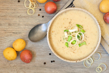 Wall Mural - Potato and leek soup. Top view table scene on a light wood background.