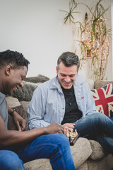 Wall Mural - A gay couple enjoying time indoors at home, playing chess. 