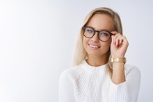 Indoor Shot Of Smart And Successful Female Entrepreneur Sharing Ways To Success Touching Frames Checking Glasses Smiling Delighted And Accomplished As Gazing Self-assured At Camera Against White Wall