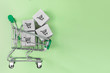 Shopping cart with boxes on green background. The concept of delivering and online shopping.